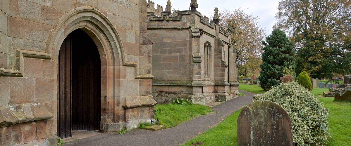 A stone church with an arched entrance and a graveyard with headstones.