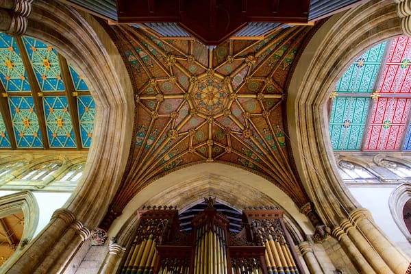 L’intérieur d’une cathédrale, avec ses vitraux richement décorés, un plafond en bois finement travaillé et un orgue à tuyaux.