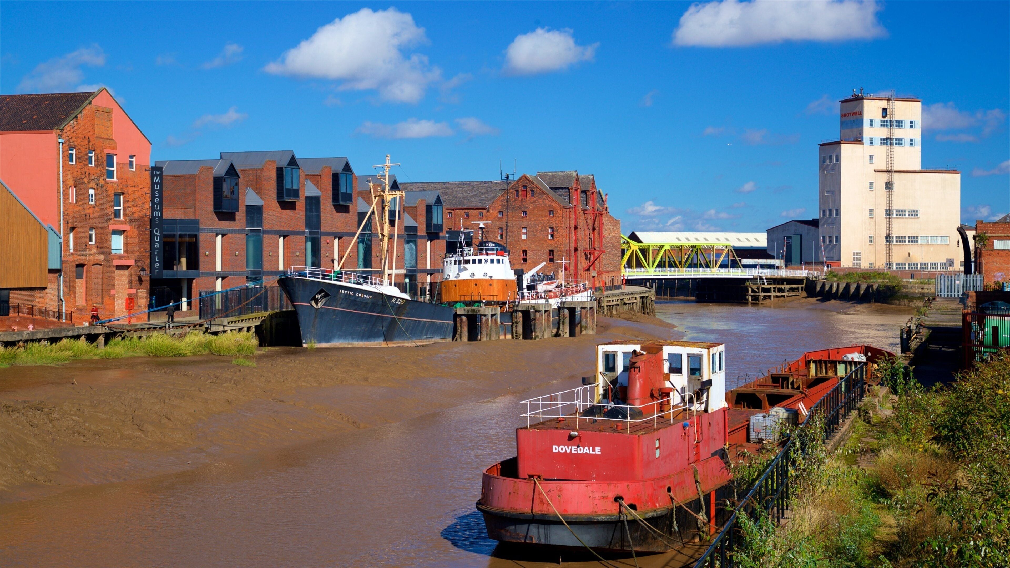 Een rivier met boten, een brug en industriële gebouwen.