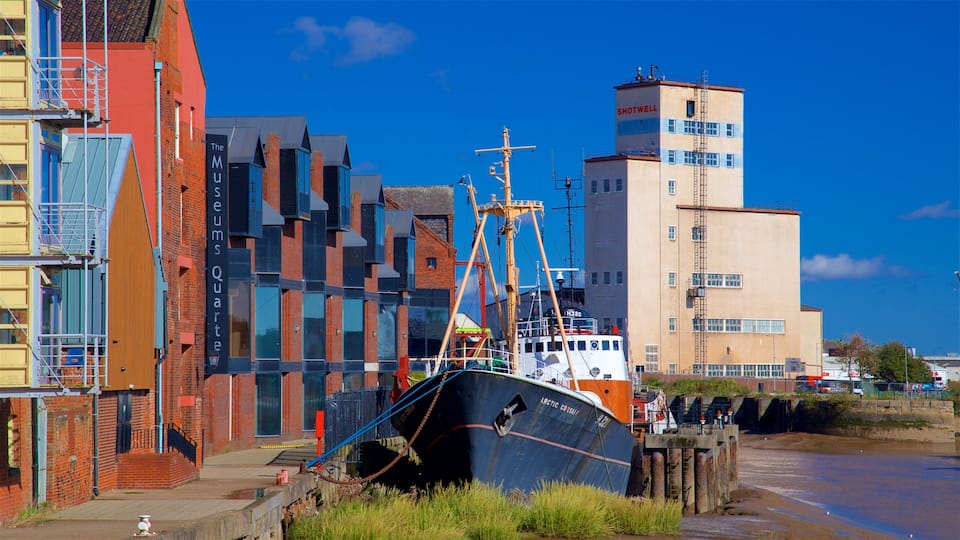 Un barco grande atracado en una orilla con edificios coloridos al fondo.