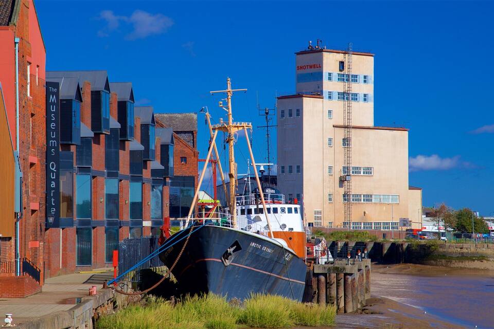 A large ship docked by a waterfront with colorful buildings in the background.