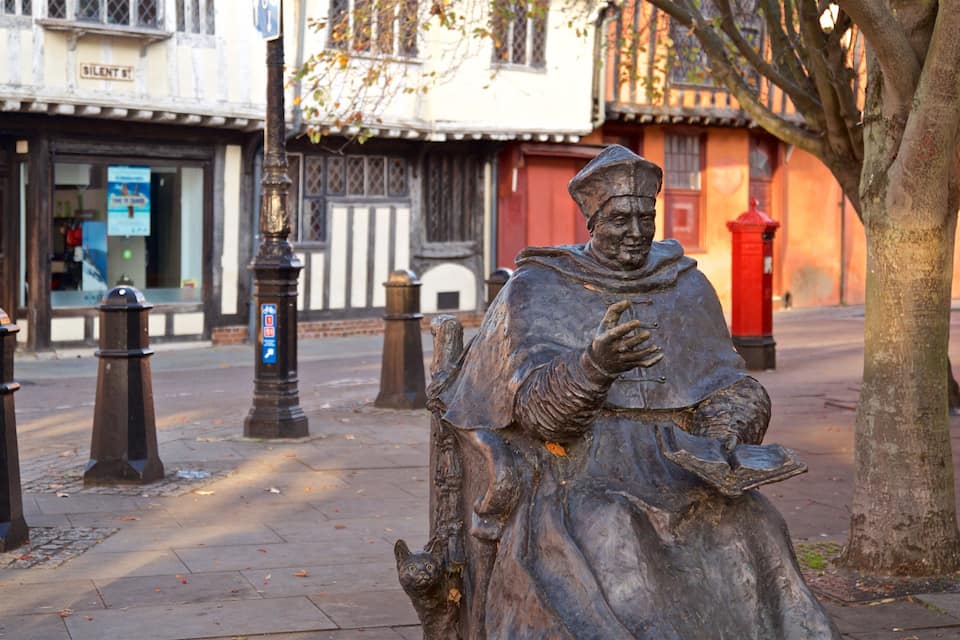Una estàtua d'un home amb roba d'època al carrer d'una ciutat.