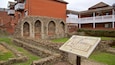 Ruinas antiguas con arcos de piedra, un muro de piedra y un cartel.