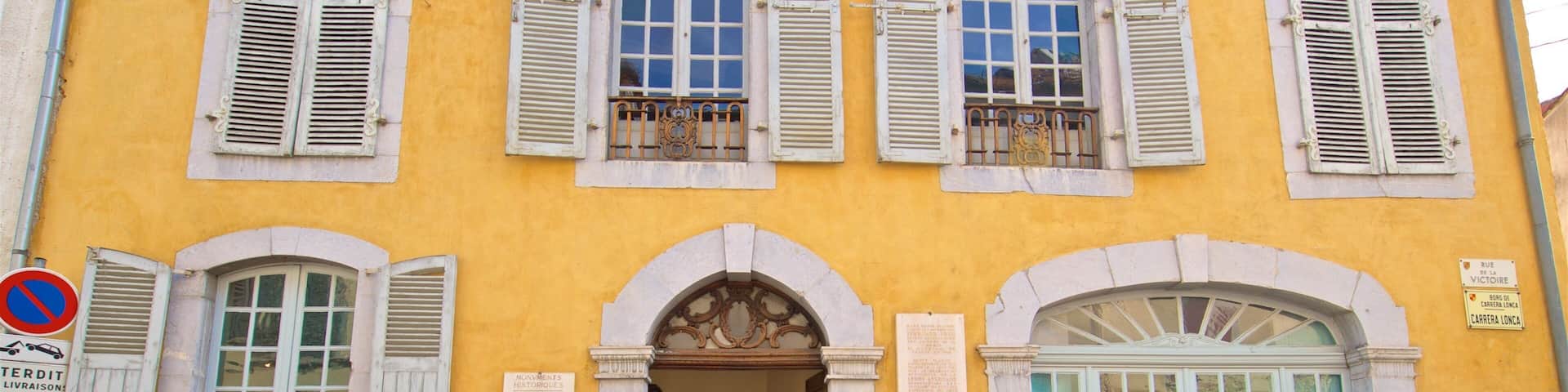 A yellow building with white shutters and a sign that reads "RUE DE LA VICTOIRE".