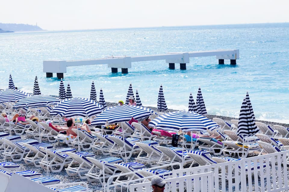 Una platja amb files de gandules blanques i sombrerets blaus i blancs.
