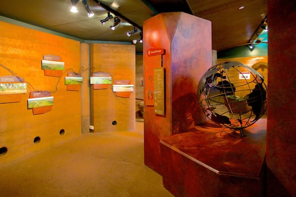 An indoor exhibit with orange walls, a globe, and informational plaques.
