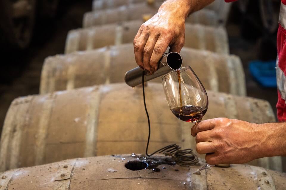 Una persona sirve vino de una botella a una copa.
