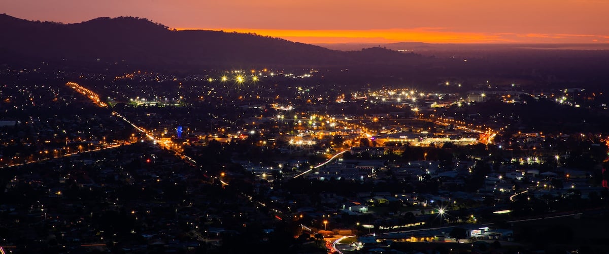 A city at dusk with a sunset over the hills.