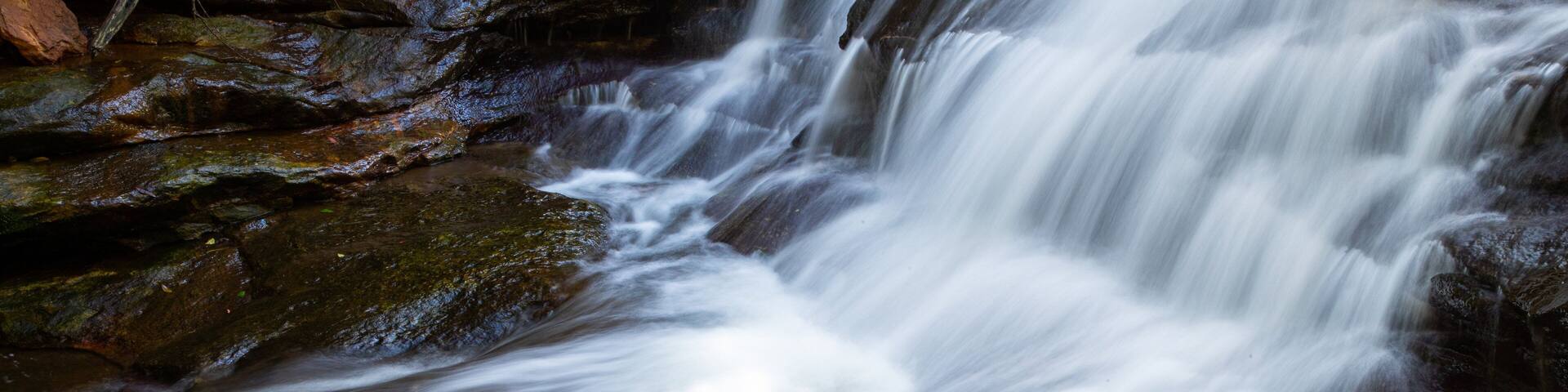 A waterfall cascading over rocks in a forested area.