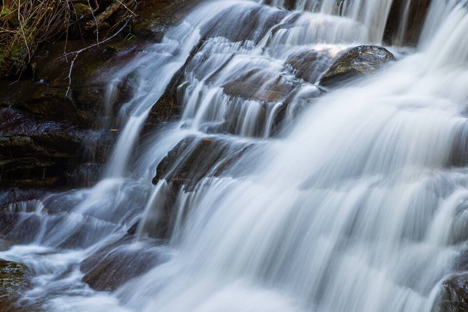 Una cascata a più livelli con acqua che scorre sulle rocce.