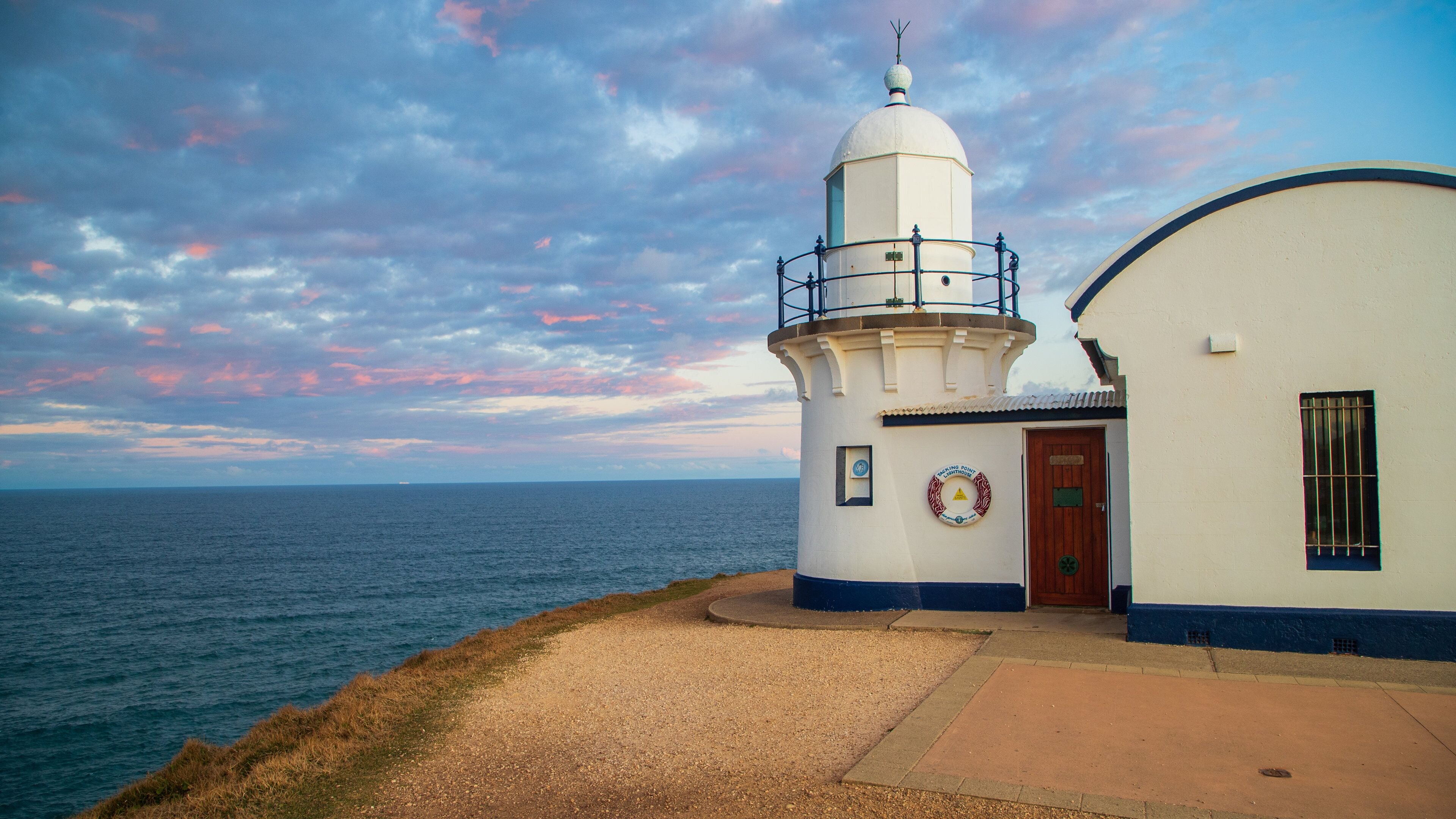 A lighthouse with a white and blue exterior, a wooden door, and a circular plaque on the wall.