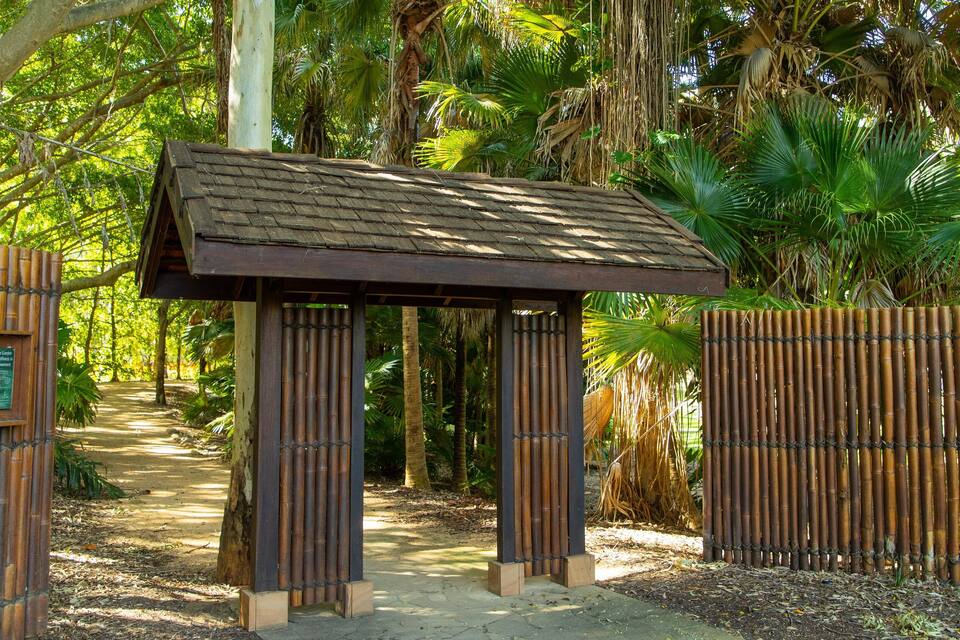 Um portão de bambu com um abrigo de madeira em um jardim tropical.
