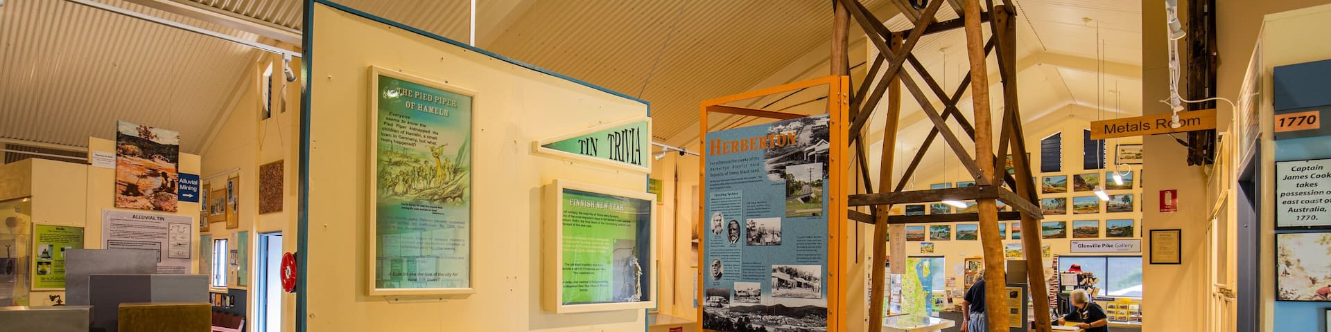 Una exhibición de museo con muestras sobre eventos históricos, incluyendo una sección dedicada al Flautista de Hamelín, una exhibición de cristales de cuarzo y una estructura de madera que se asemeja a una grúa.