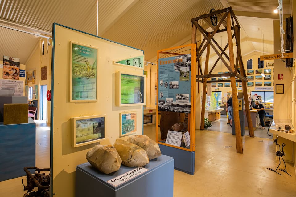 A museum exhibit with displays on historical events, including a section on the Pied Piper of Hameln, a display of quartz crystals, and a wooden structure resembling a crane.