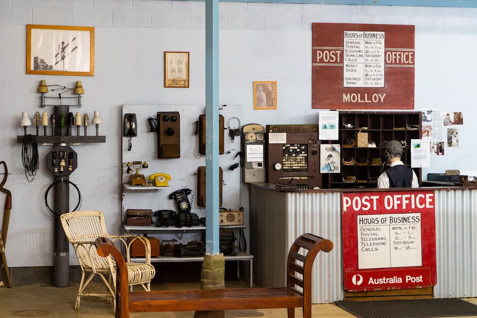 A vintage post office with a sign listing hours of business.