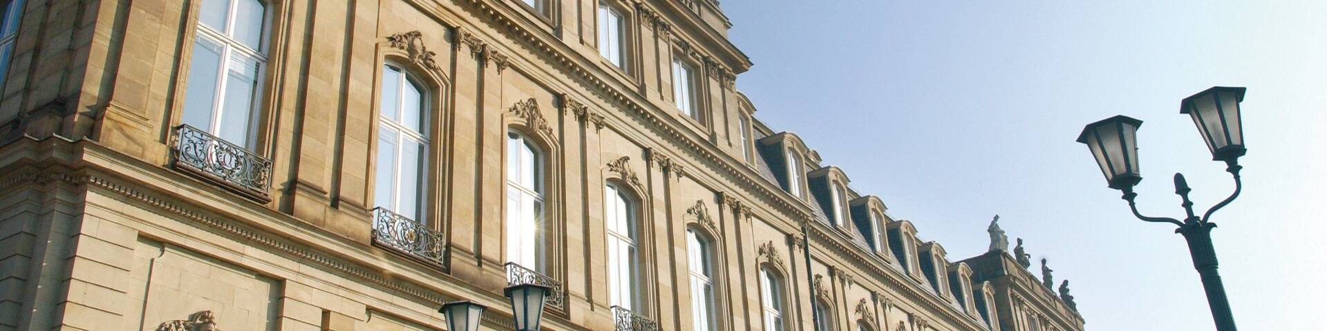 A historic building with ornate architecture, large windows, and statues on the roof.