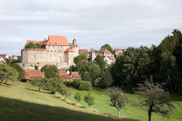 Un château historique, entouré d’une végétation luxuriante et de maisons traditionnelles.