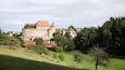A historic castle surrounded by lush greenery and traditional houses.