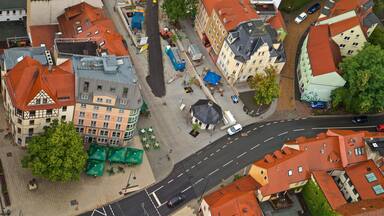 Vista aérea de uma cidade europeia com edifícios históricos, uma estrada sinuosa e áreas de estar ao ar livre.