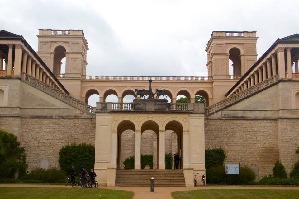 Um edifício histórico com um arco central, duas torres e uma estátua no topo.