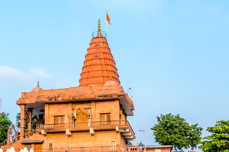 A temple with a tall spire and a flag on top.