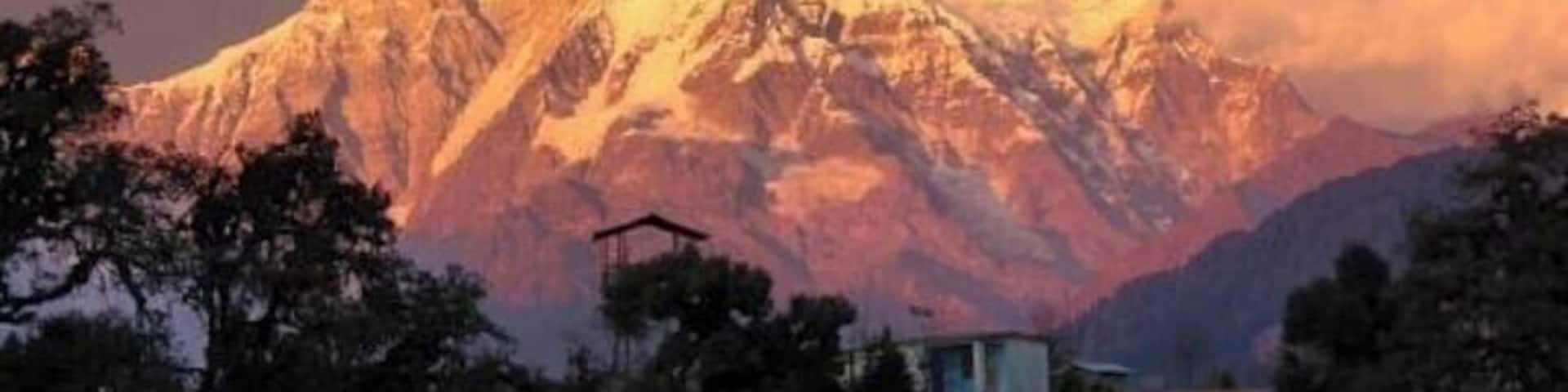 Una cordillera nevada con un edificio pequeño en primer plano.