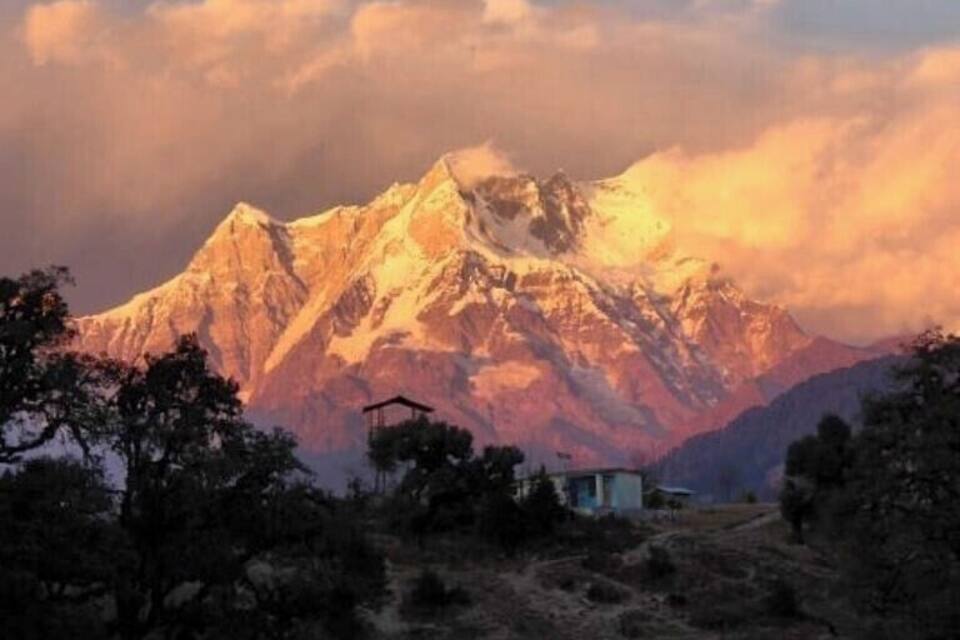 A snow-capped mountain range with a small building in the foreground.