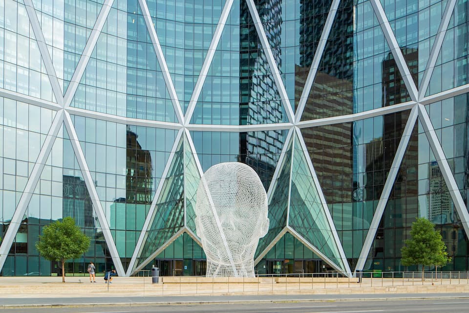 Un edifici modern de vidre amb una escultures geomètriques singular al davant.