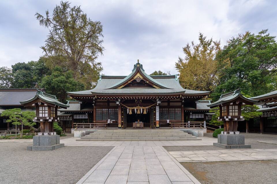 A traditional Japanese temple with a central hall, surrounded by stone lanterns and a stone pathway.