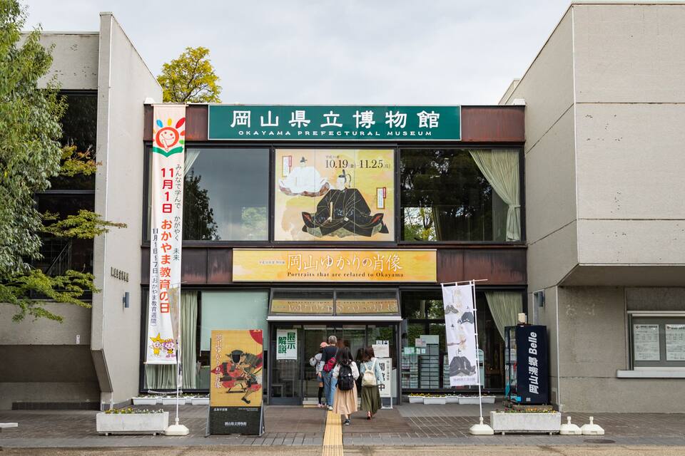 L’entrée du musée préfectoral d’Okayama, avec une grande affiche représentant une figure historique et un panneau d’information en japonais.