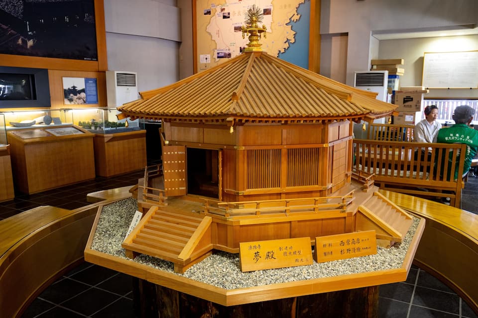 Un modèle traditionnel de pavillon japonais, doté d’un toit en tuiles, d’une structure en bois et d’une base entourée de gravier.
