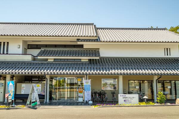Un bâtiment traditionnel japonais, avec un toit recouvert de tuiles et une enseigne devant l’entrée.