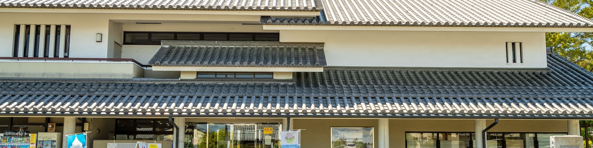 Um edifício japonês tradicional com telhado em telhas e uma placa em frente.