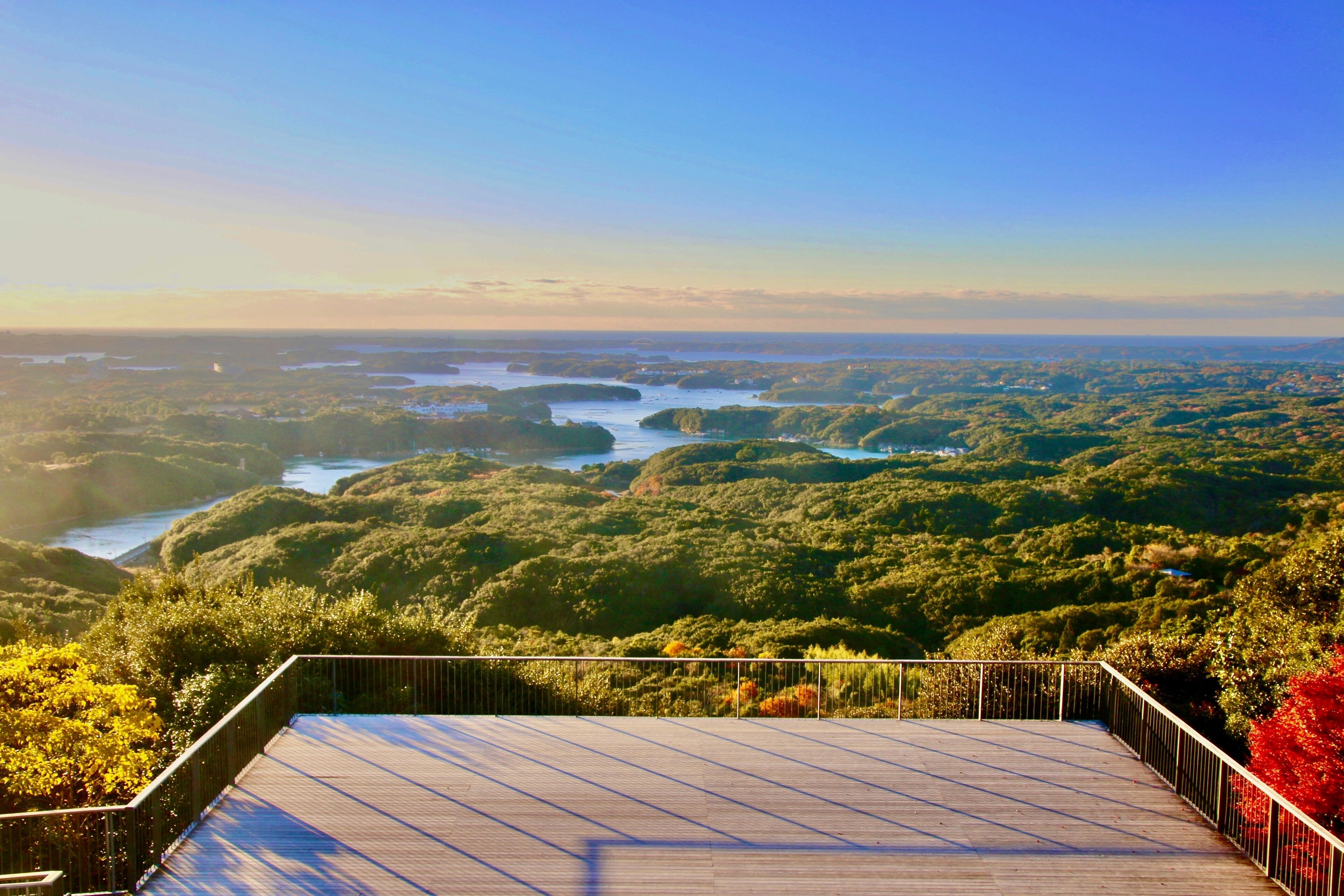 A wooden observation deck overlooking a lush landscape with dense greenery and a river.