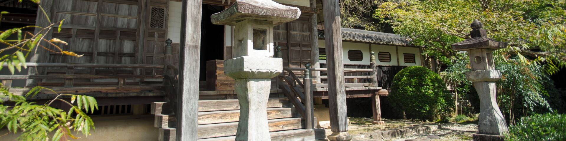 A traditional Japanese temple with ornate architecture, stone lanterns, and a serene garden setting.
