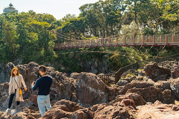 Jogasaki Suspension Bridge which includes rugged coastline and a bridge as well as a couple
