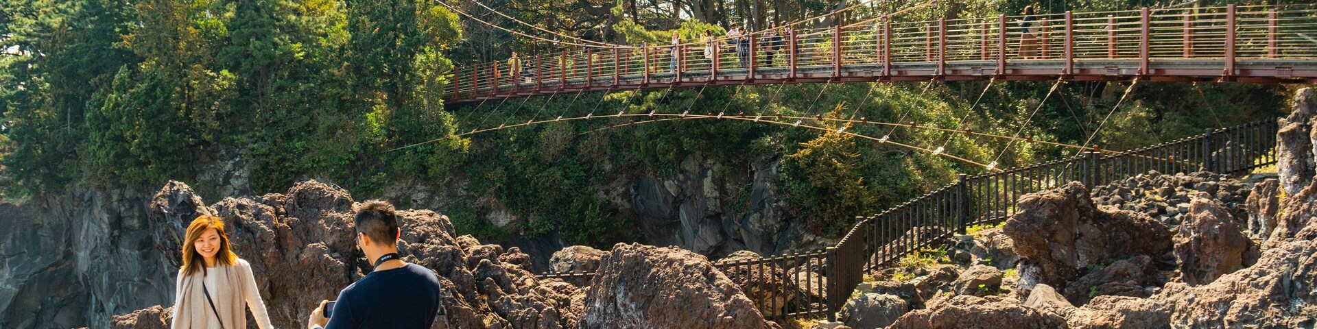 Jogasaki Suspension Bridge which includes rugged coastline and a bridge as well as a couple