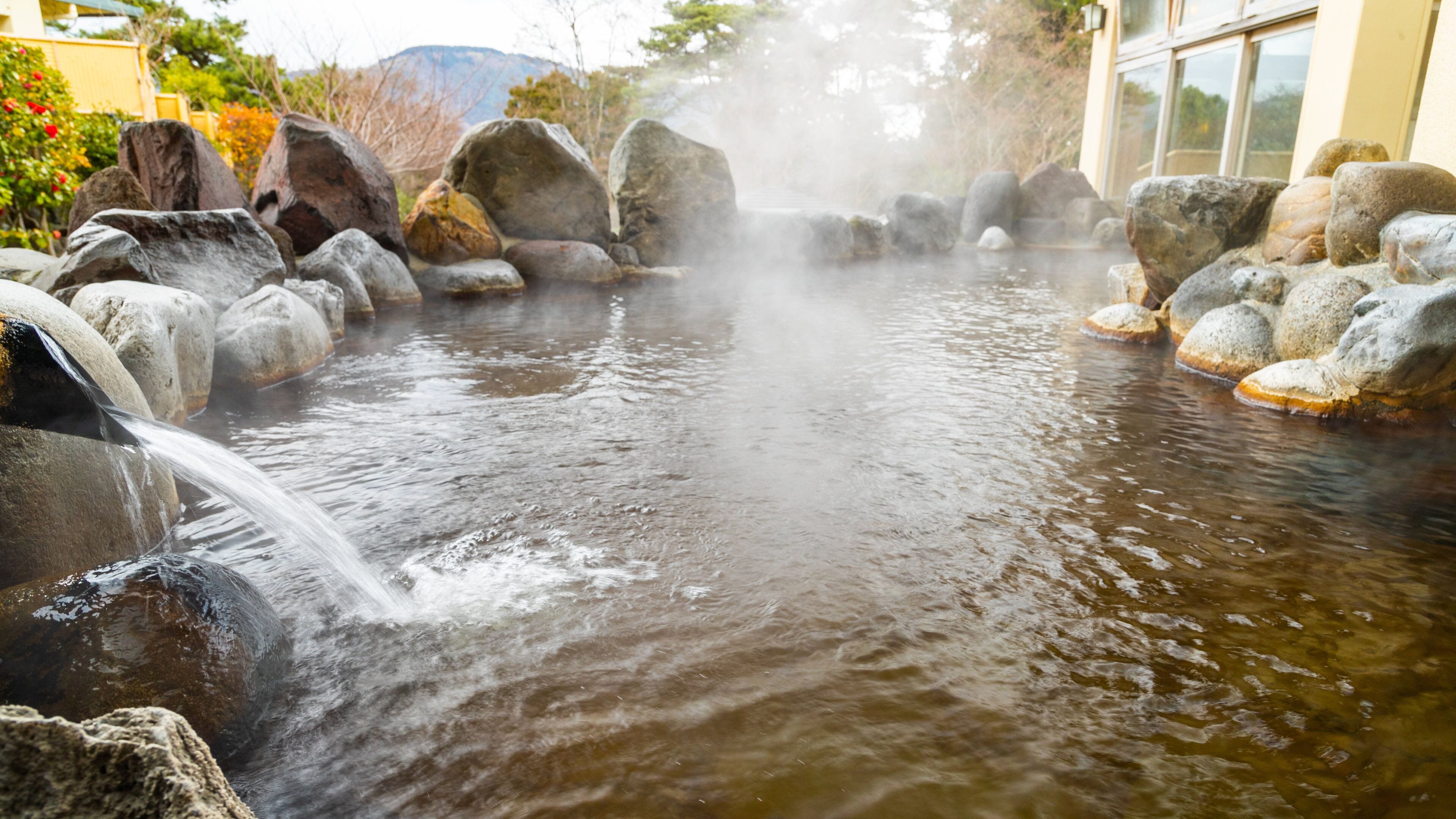 Eine heiße Quelle mit Wasser, das über Felsen fließt, und aufsteigendem Dampf.