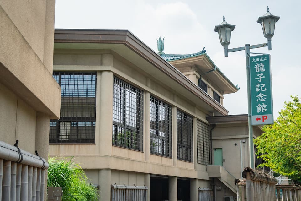 A traditional Japanese building with large windows and a green sign.