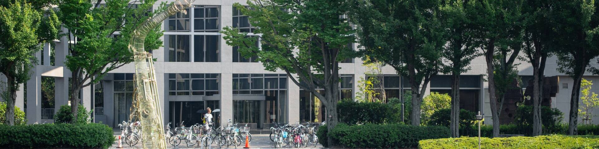 A park with a pond, steps leading to a building, and bicycles parked nearby.