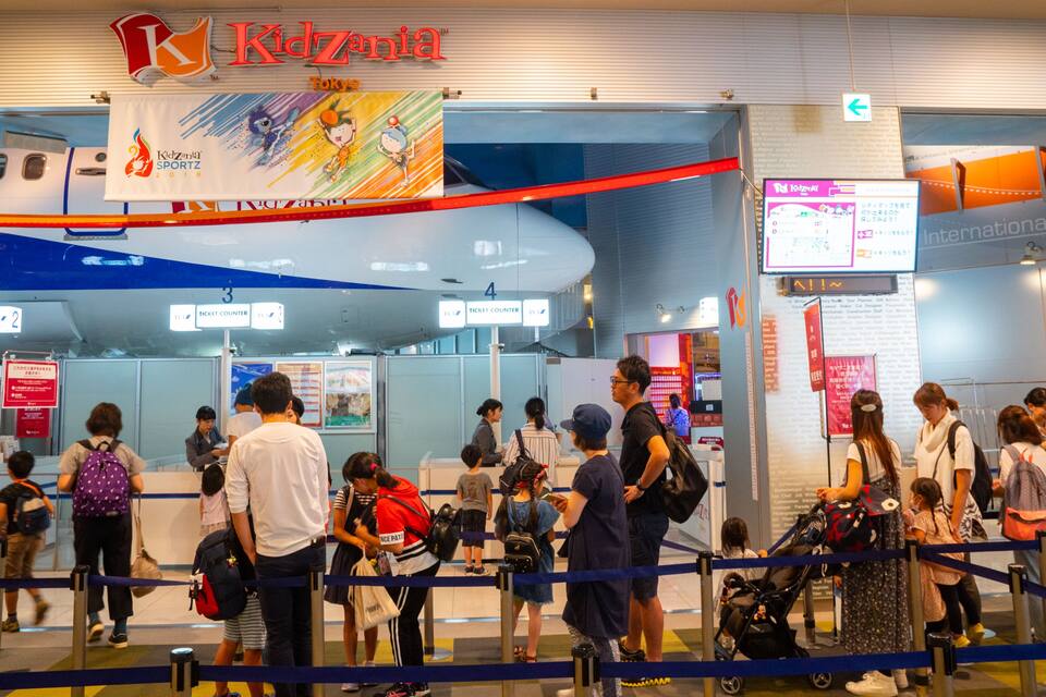 Una terminal d'aeroport animada, amb taquilles i un gran cartell de Kidzania Tòquio 2018.