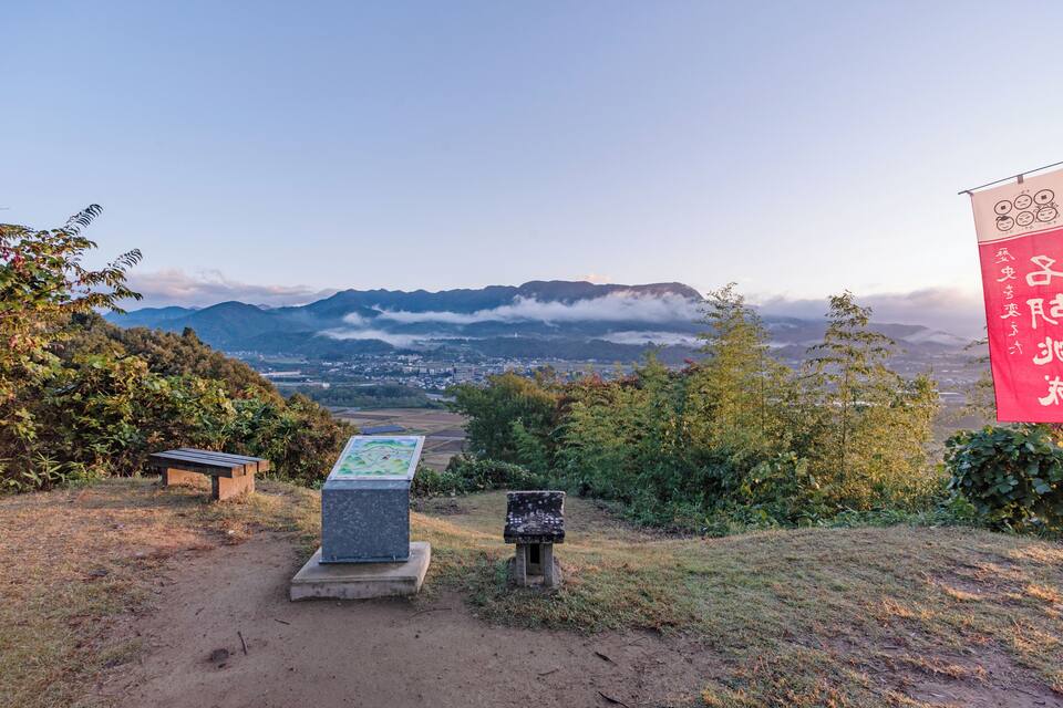 A scenic overlook with a view of a town and mountains in the distance.