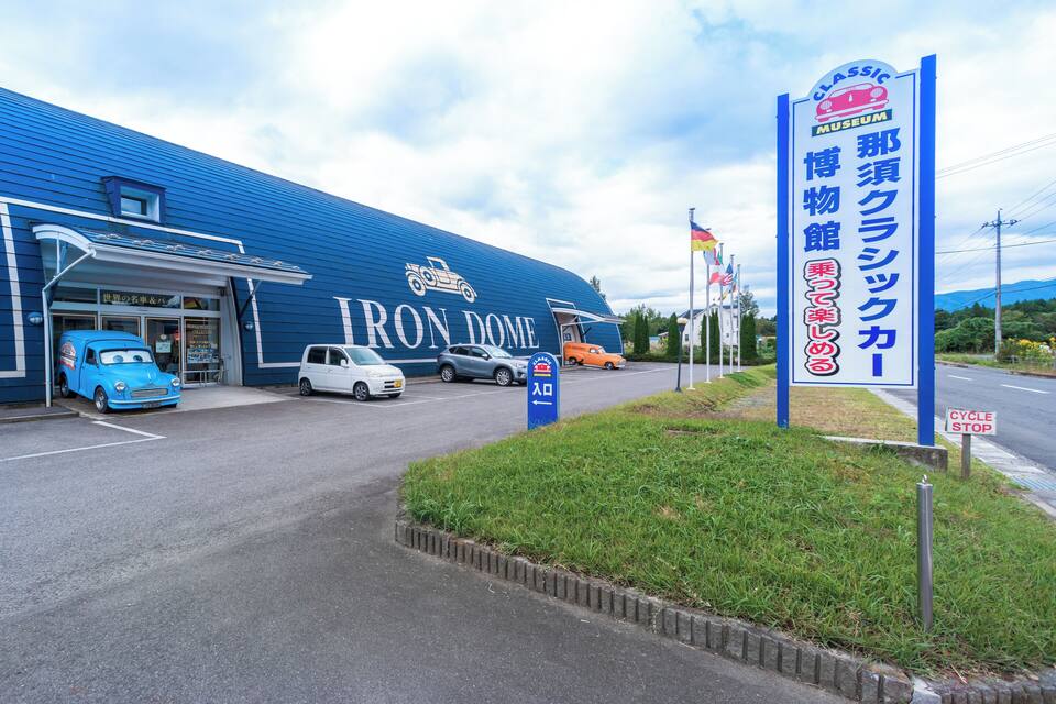 Een blauw gebouw met een bord voor het Iron Dome museum en een tentoonstelling van klassieke auto's.
