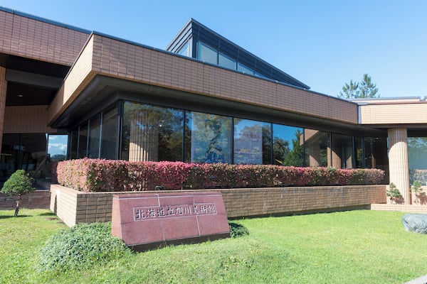 A modern building with large glass windows, a brick facade, and a sign in front.