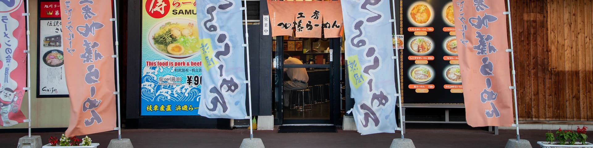 A restaurant with Japanese signage and multiple food-related banners.