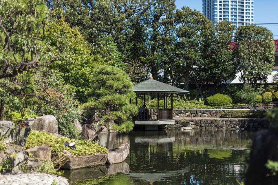 Um jardim tranquilo com lago, pedras e um coreto.