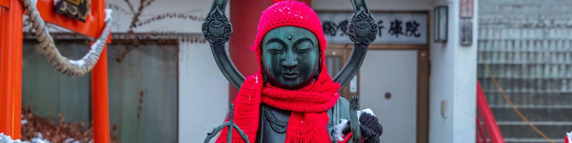 A statue of a figure with a red scarf and a halo, surrounded by white paper decorations.