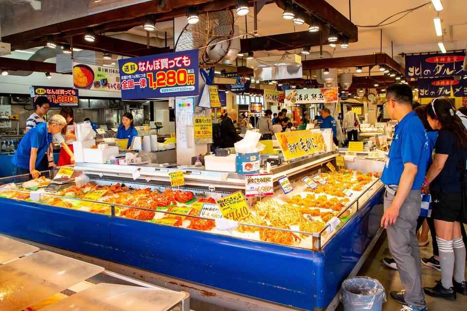 A bustling market with a seafood display and various signs in Japanese.