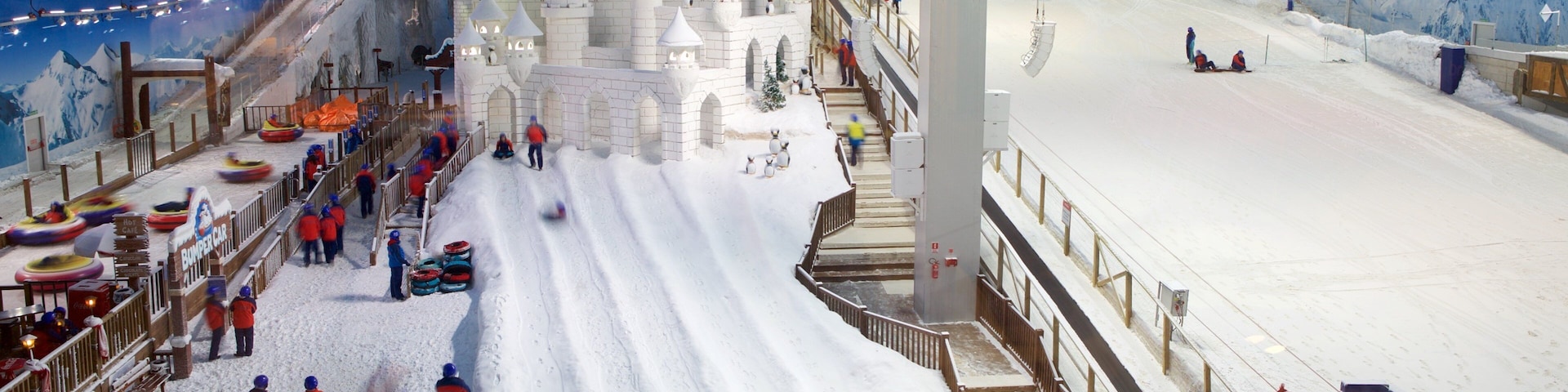 An indoor snow park with a snow castle, a ski slope, and a snow tubing area.