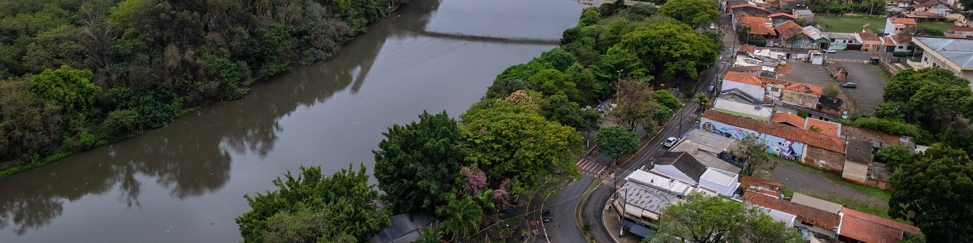 A river flowing through a city with dense greenery, a bridge, and high-rise buildings.